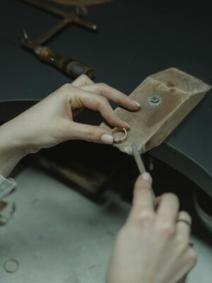 Close-up of a jeweler using hand tools to craft a gold ring in an artisan workshop.